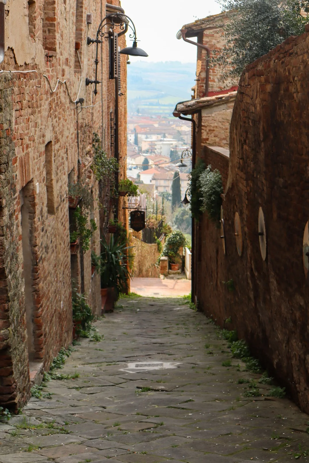 Un vicolo lastricato del borgo di Vinci, con la campagna toscana sul fondo